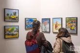 Een aantal schilderijen met bezoekers tijdens Art Rotterdam in de Van Nelle Fabriek in Rotterdam