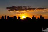 De ondergaande zon boven het centrum van Rotterdam met de stad als silhouet