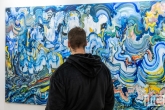 Een kleurig schilderij met bezoeker tijdens Art Rotterdam in de Van Nelle Fabriek in Rotterdam