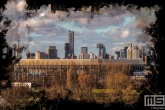 Te Koop | Een detailfoto van het Feyenoord Art Stadion De Kuip met op de achtergrond de skyline van Rotterdam