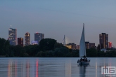 Het uitzicht op de skyline van Rotterdam met een zeilboot op de Kralingseplas