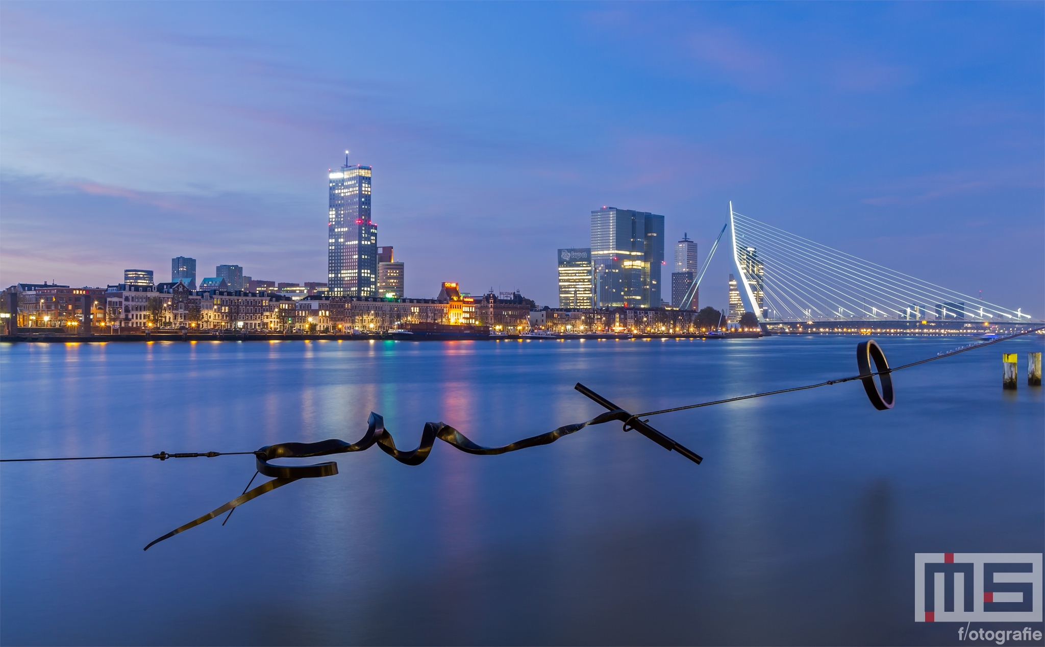 Te Koop | Het Maasbeeld (Wasknijper) in de avond met het Noordereiland, Erasmusbrug en De Maas