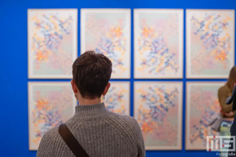 Een schilderij met bezoekers tijdens Art Rotterdam in de Van Nelle Fabriek in Rotterdam