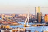 De gouden zonsondergang in Rotterdam met de Erasmusbrug en Maastoren