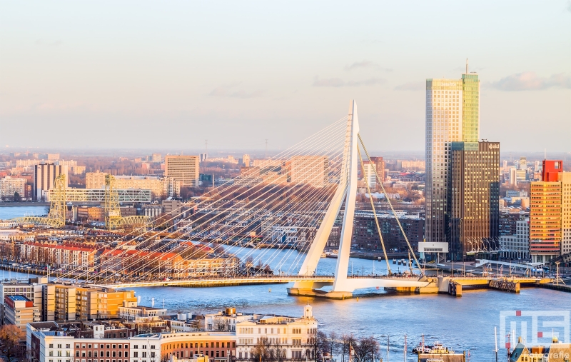 De gouden zonsondergang in Rotterdam met de Erasmusbrug en Maastoren